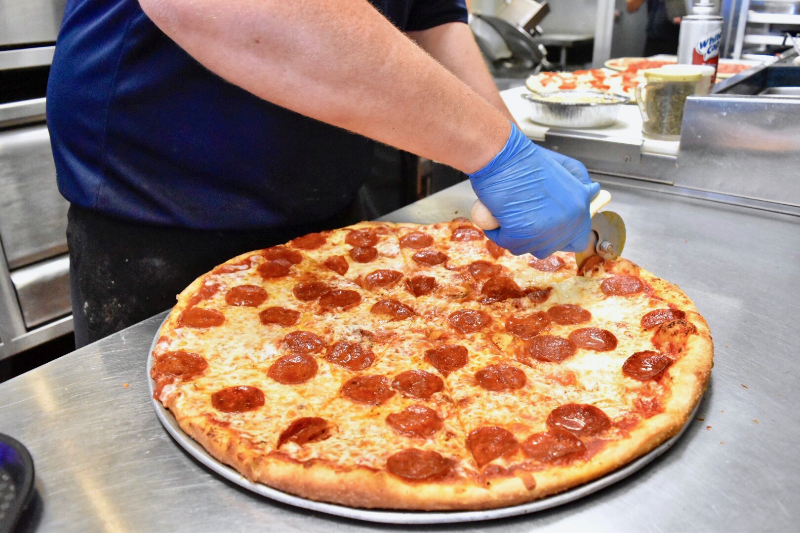 Photo of a person cutting a pepperoni pizza