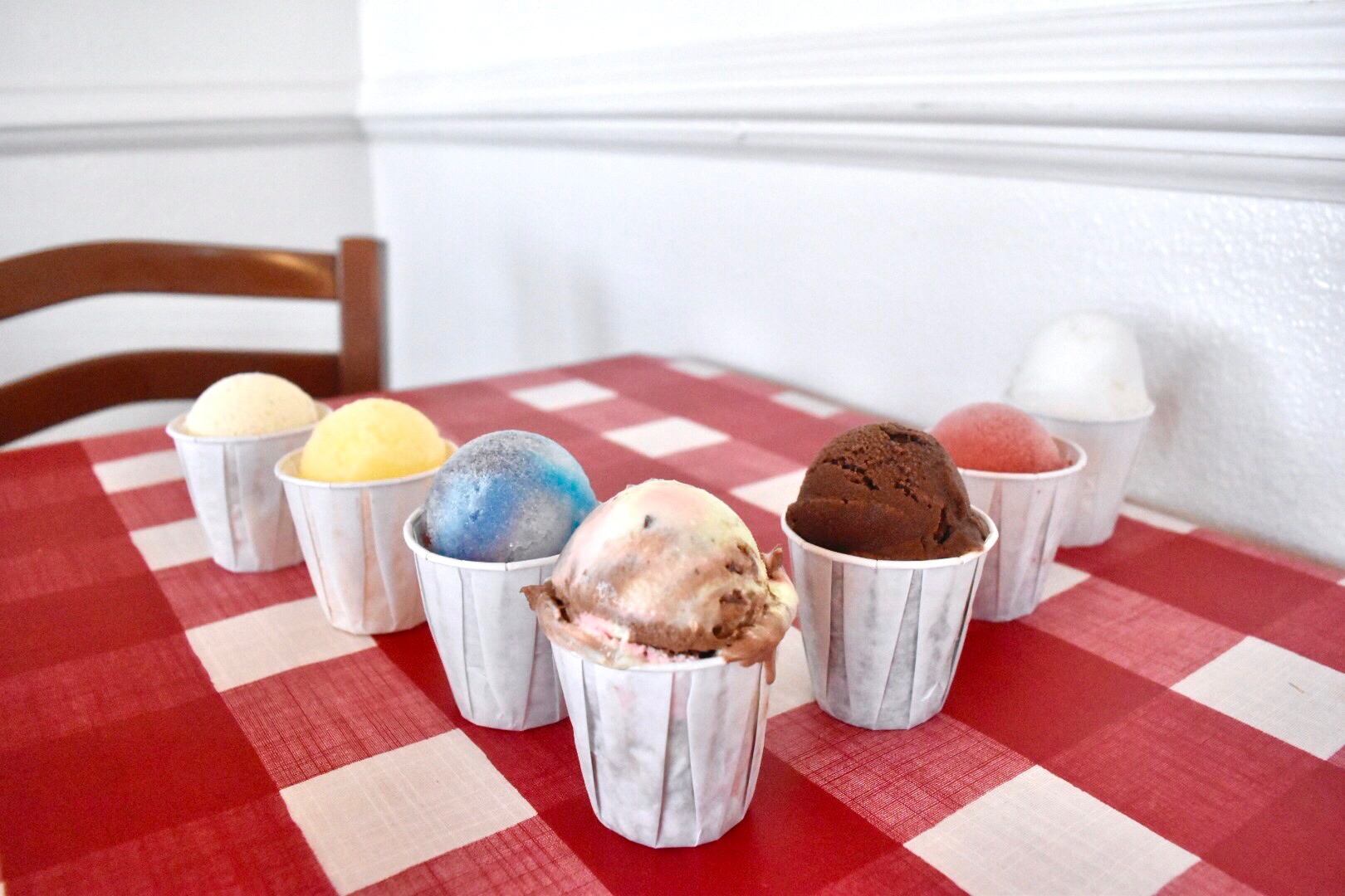 Photo of 7 diffrent flavors of italian ice cream on a table
