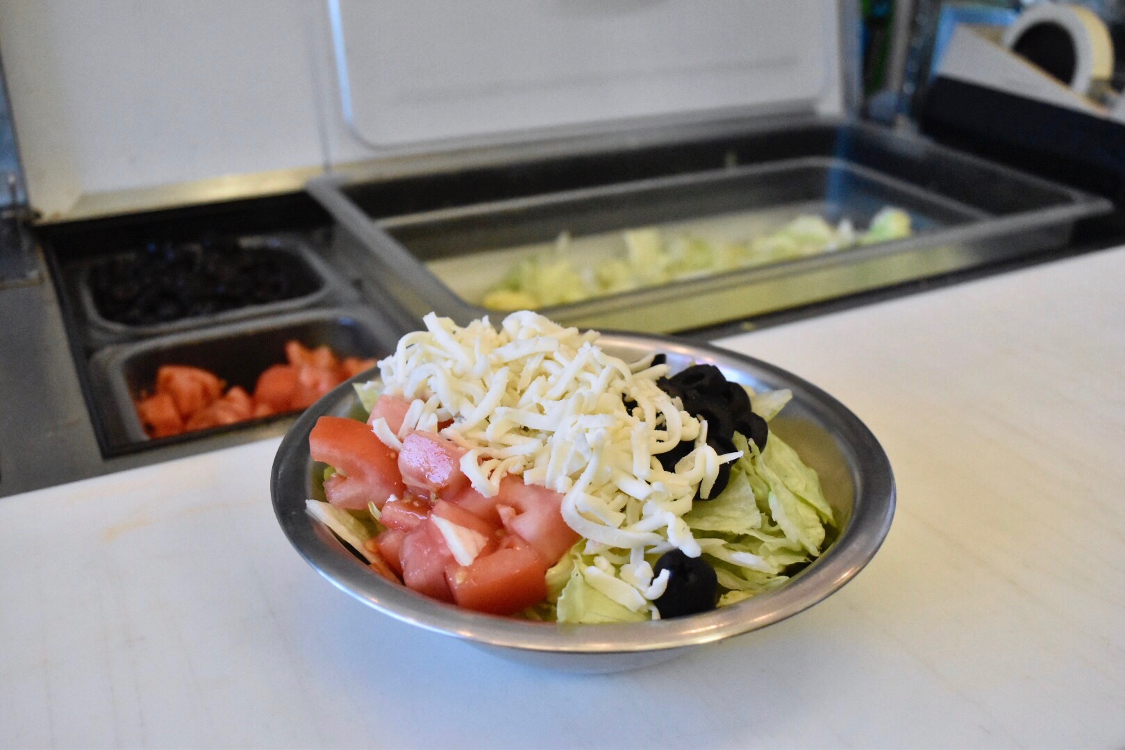 Photo of Salad on table with tomatos, cheese, and olives