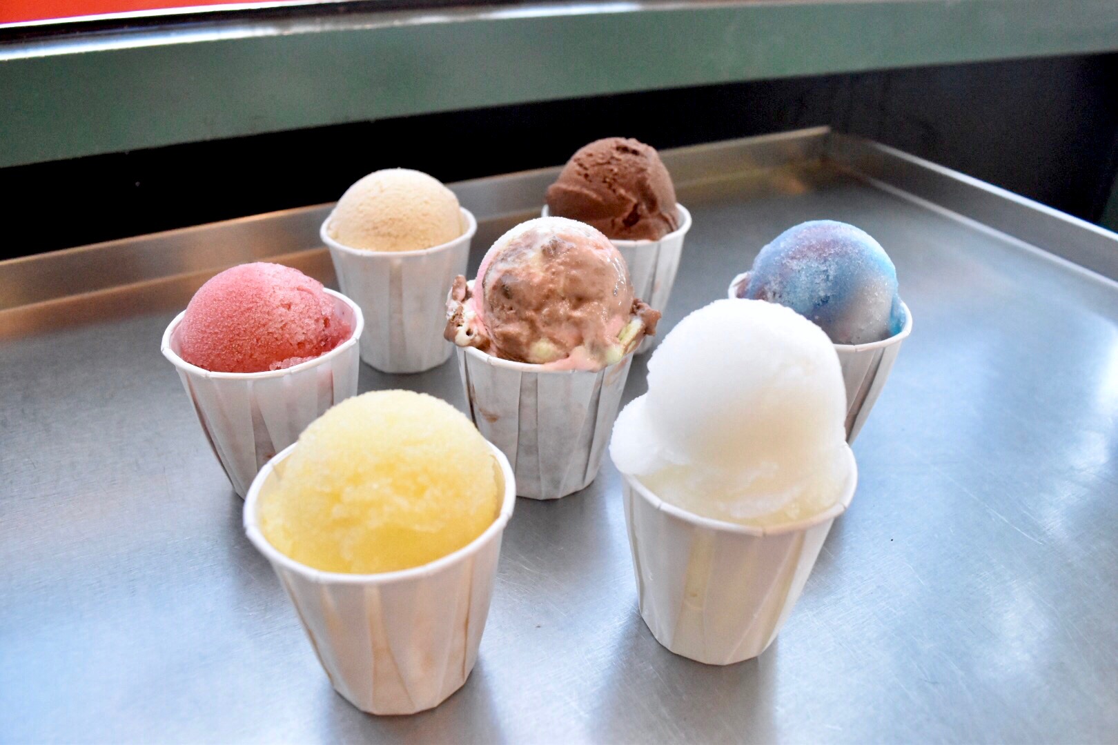 Photo of 7 diffrent flavors of italan icecreams on display on a table