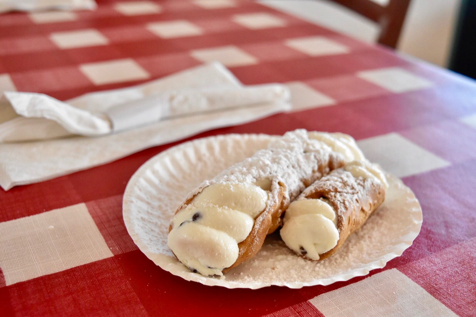 Photo of a cannoli on a table with powder sugar on top.